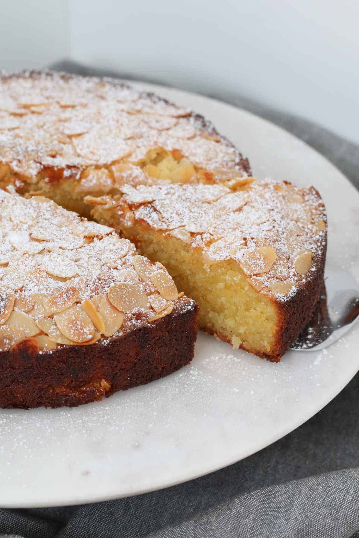 A round almond cake with one serve slightly removed.