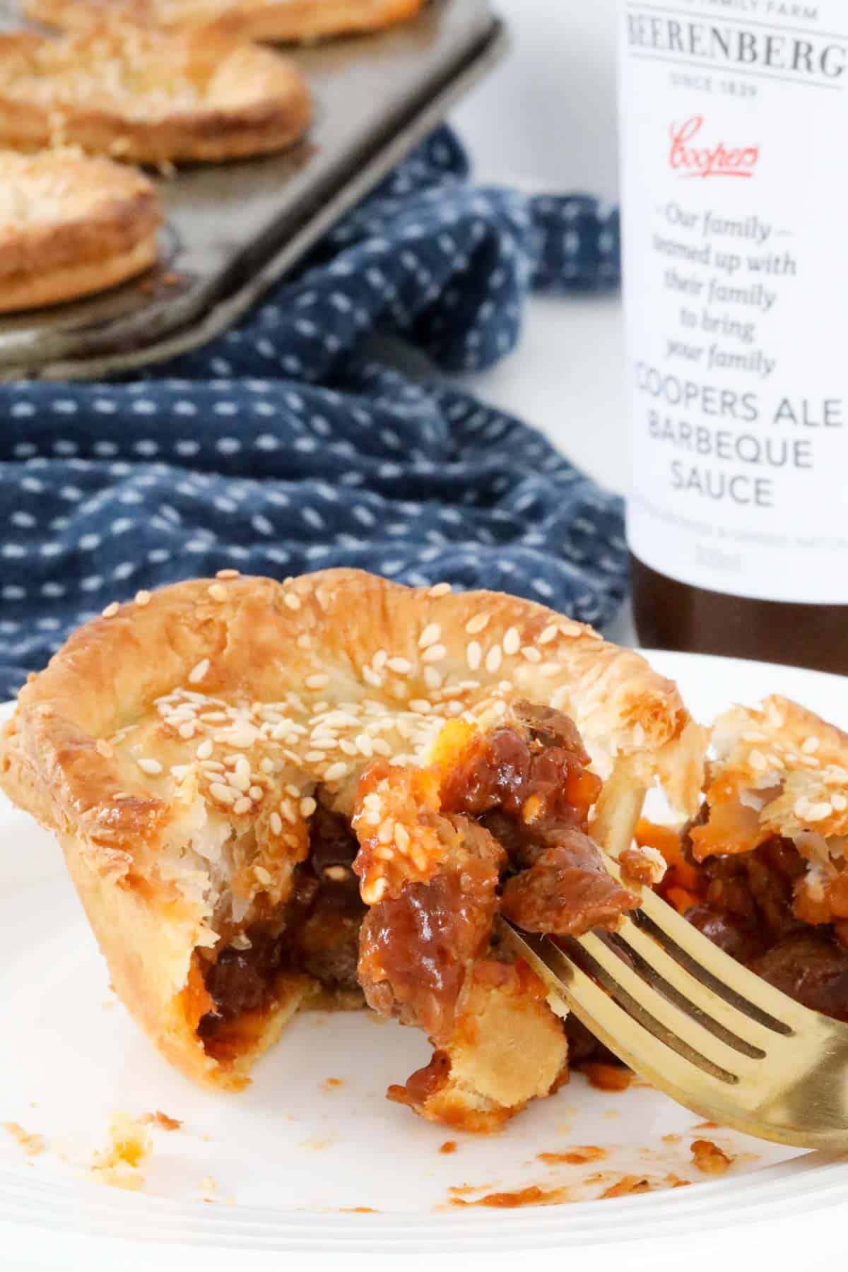 A beef party pie cut open on a plate with a fork