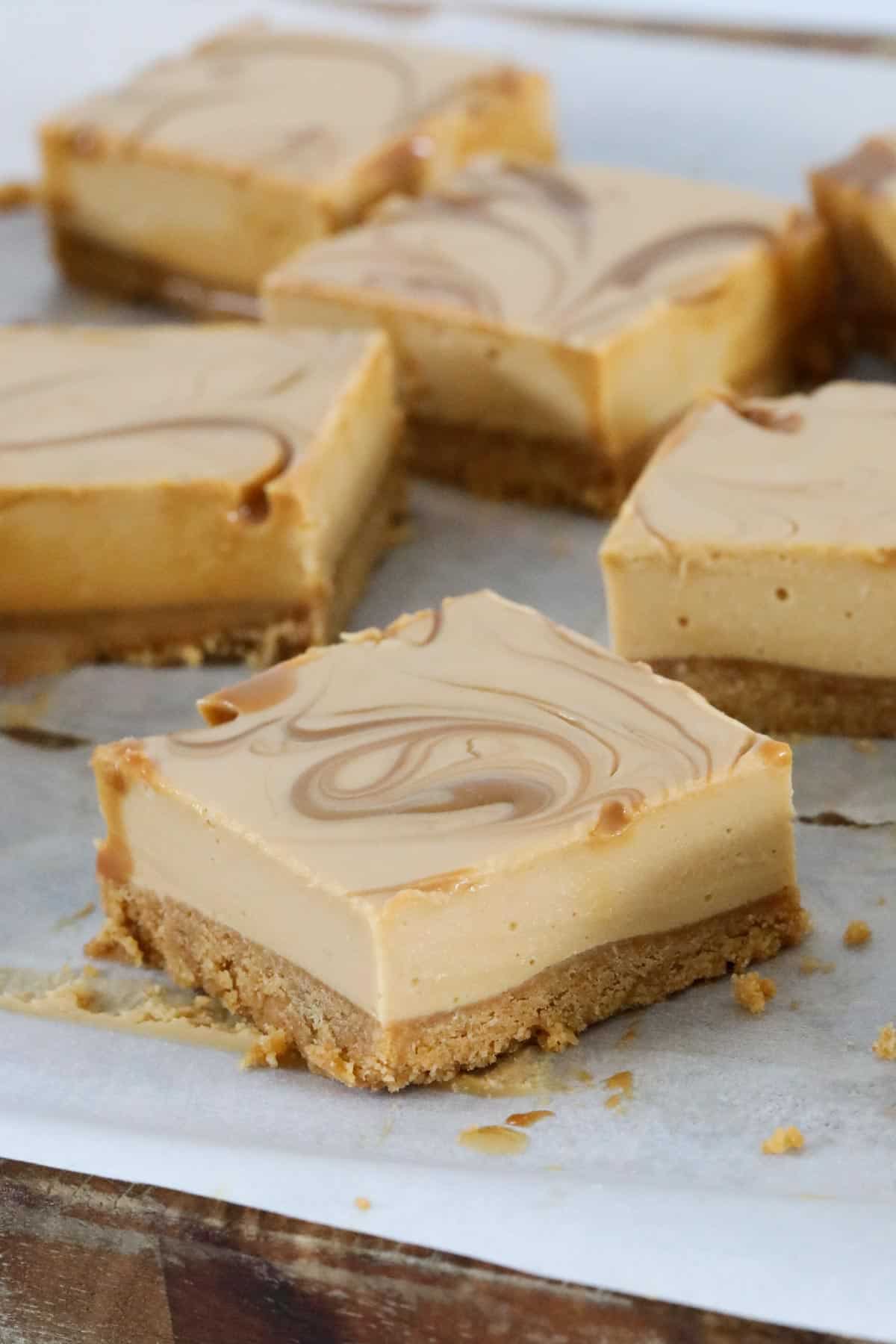 Pieces of creamy caramel bars cut up on a chopping board.