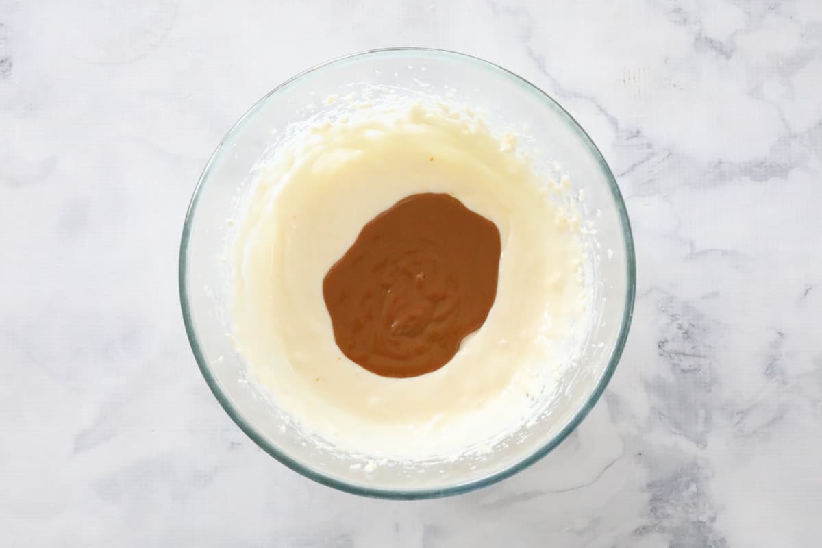Caramel sauce on top of a white cream cheese mixture in a bowl.