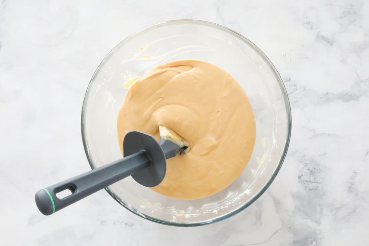 A spatula in a bowl of caramel cream cheese mixture.
