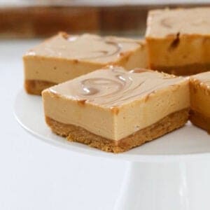 No bake caramel cheesecake pieces on a white cake stand.