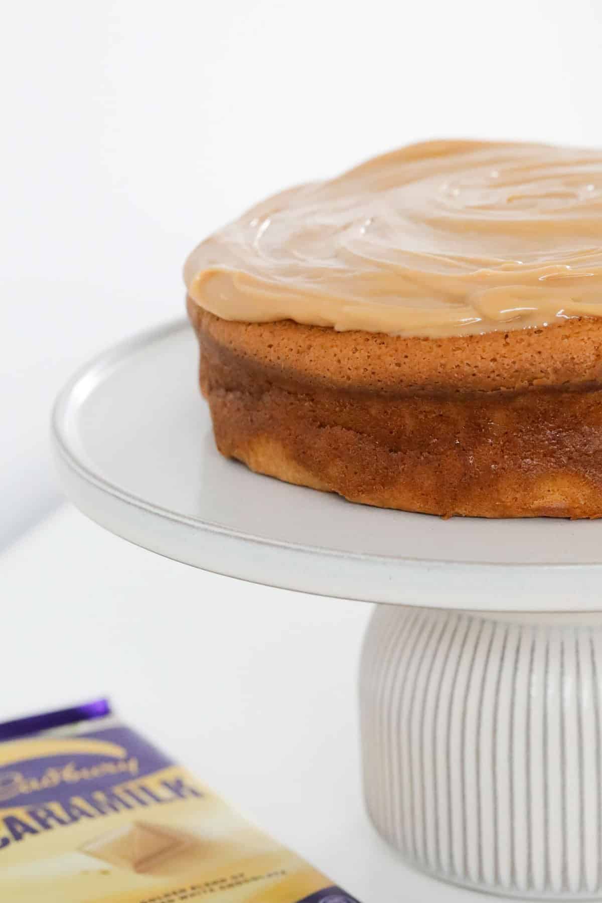A caramel cake on a white cake stand.