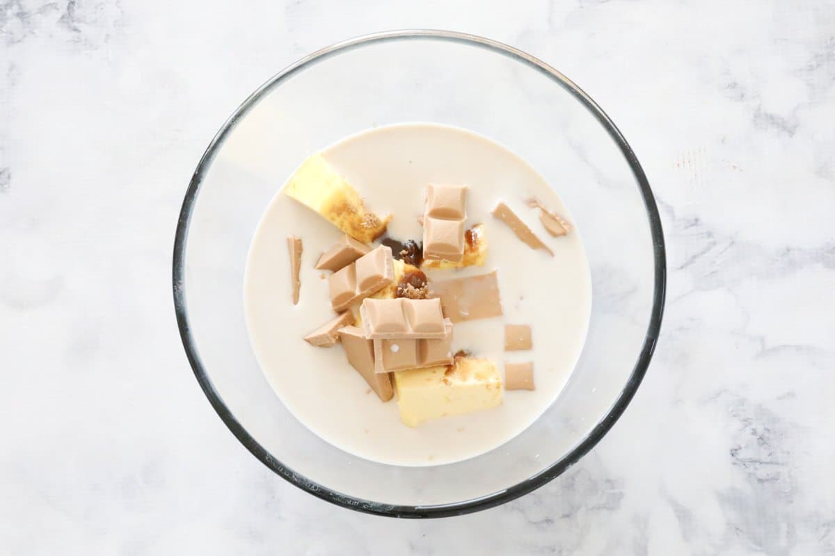 Butter, broken pieces of chocolate and milk in a glass bowl.