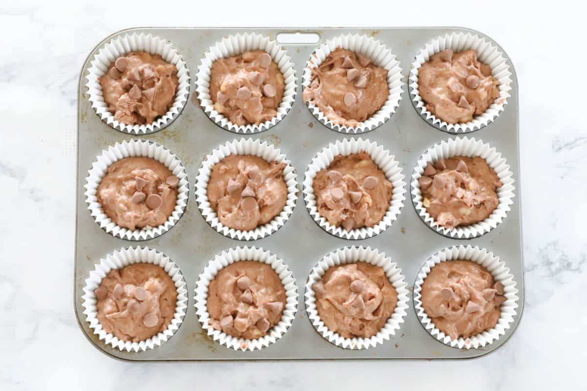Muffin mixture spooned into cases in a muffin tray, ready to be baked.