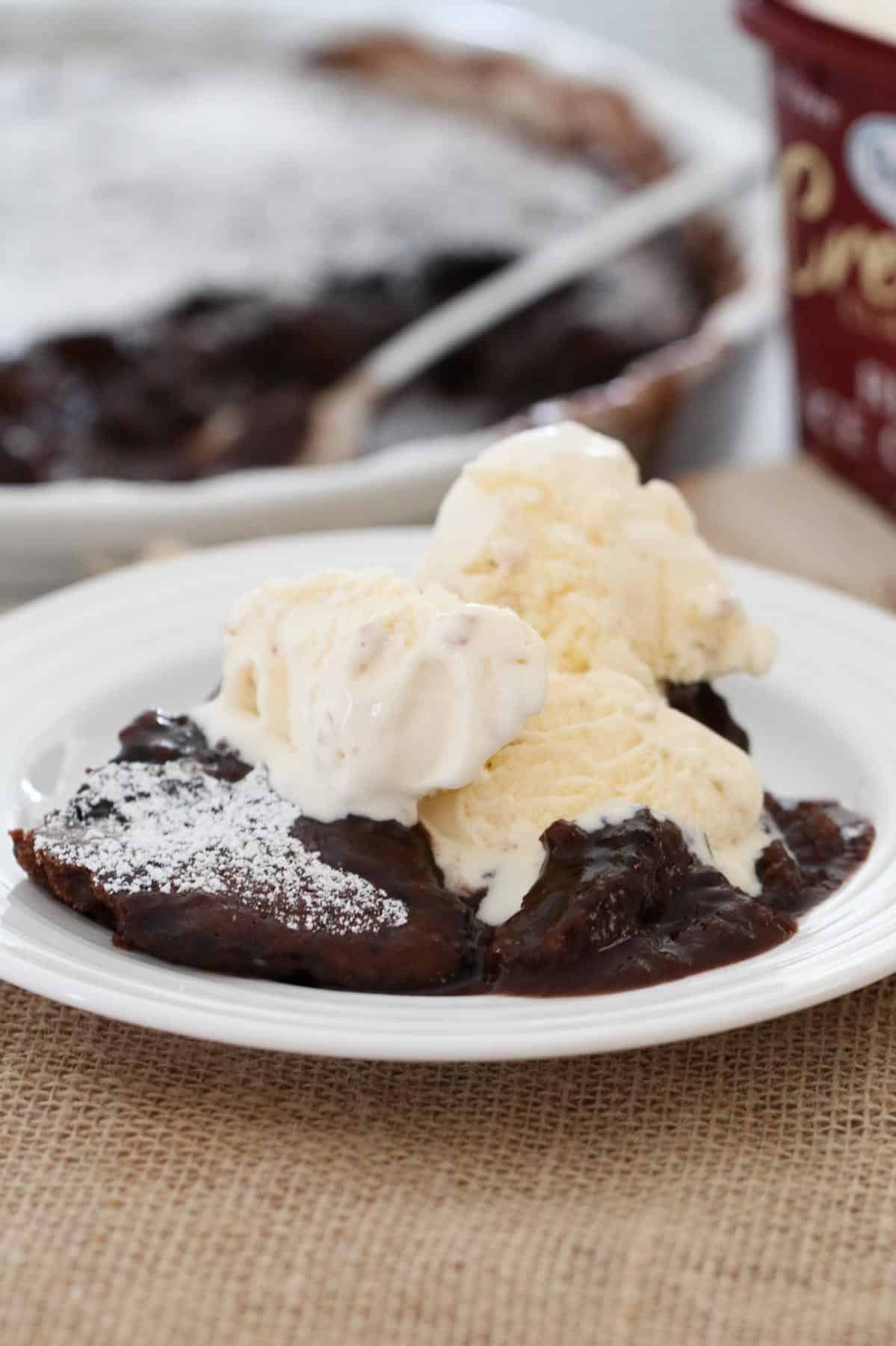Chocolate self saucing pudding served with ice cream on a plate.