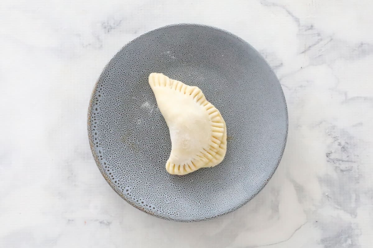 An uncooked dough triangle on a grey plate