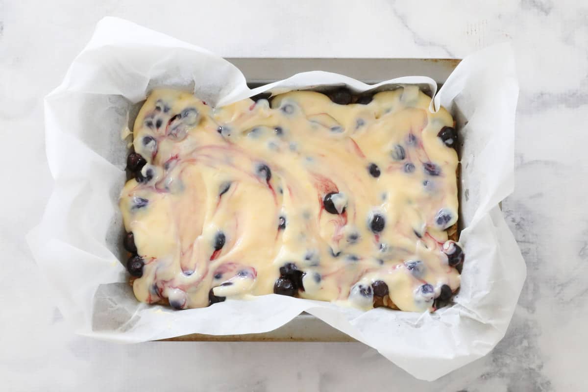Creamy lemon filling with blueberries in a slice tin.