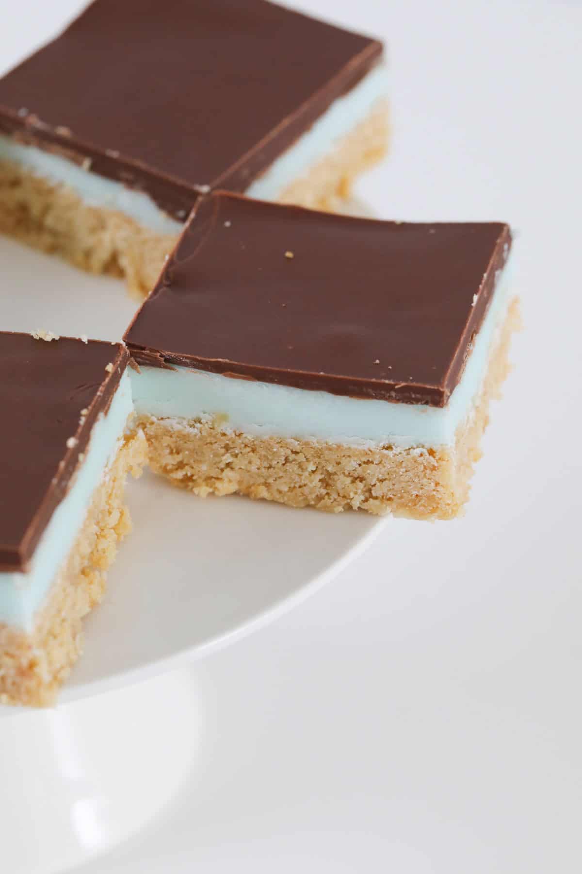 A close up of squares of slice, with a green minty filling and milk chocolate topping.