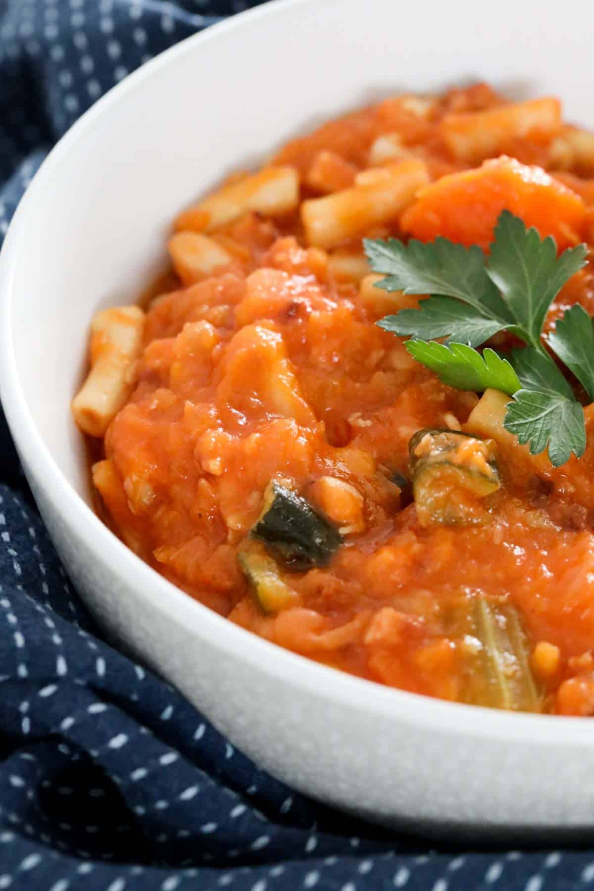 A thick vegetable, tomato and pasta soup in a bowl.
