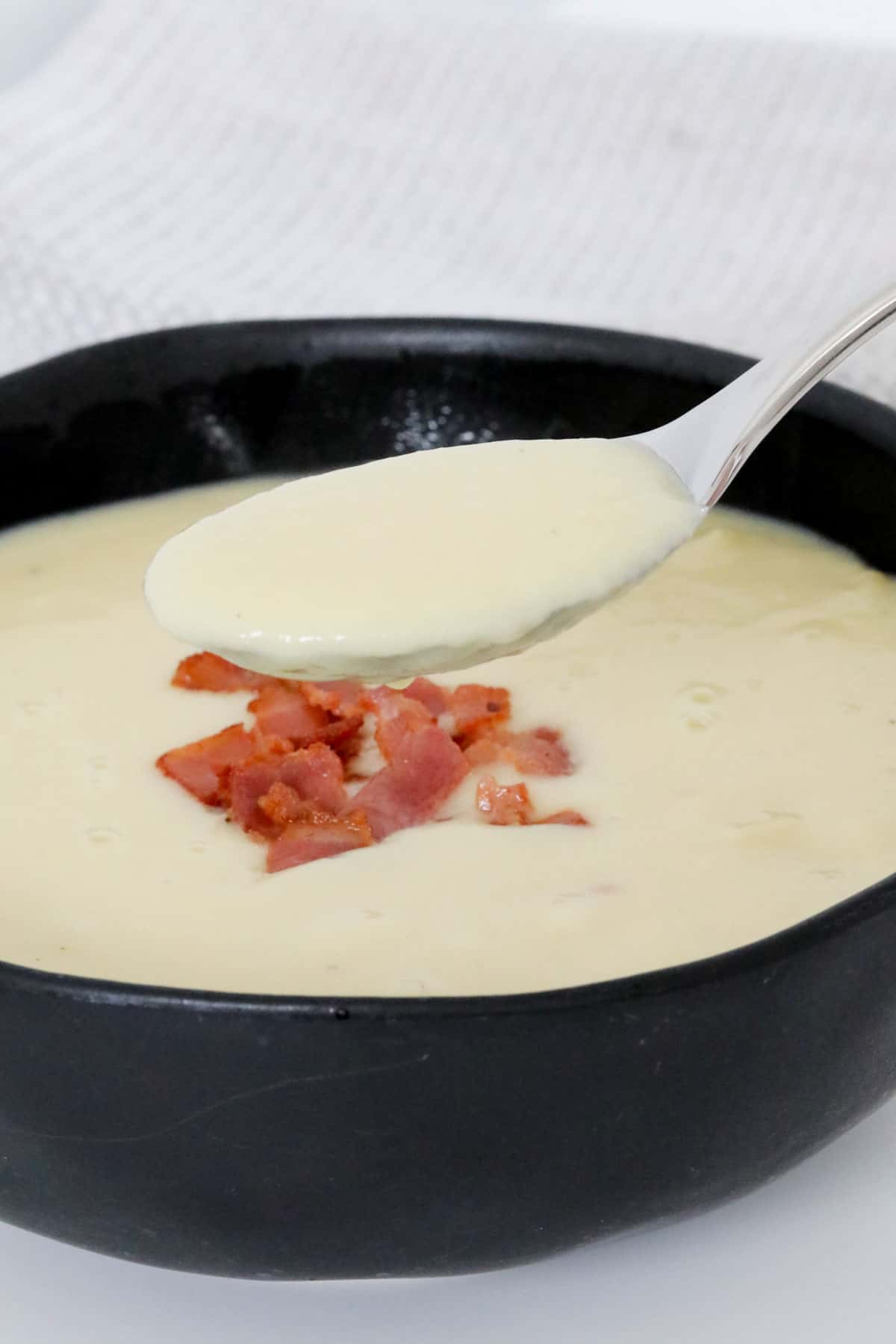 A spoonful of thick soup held over a bowl.
