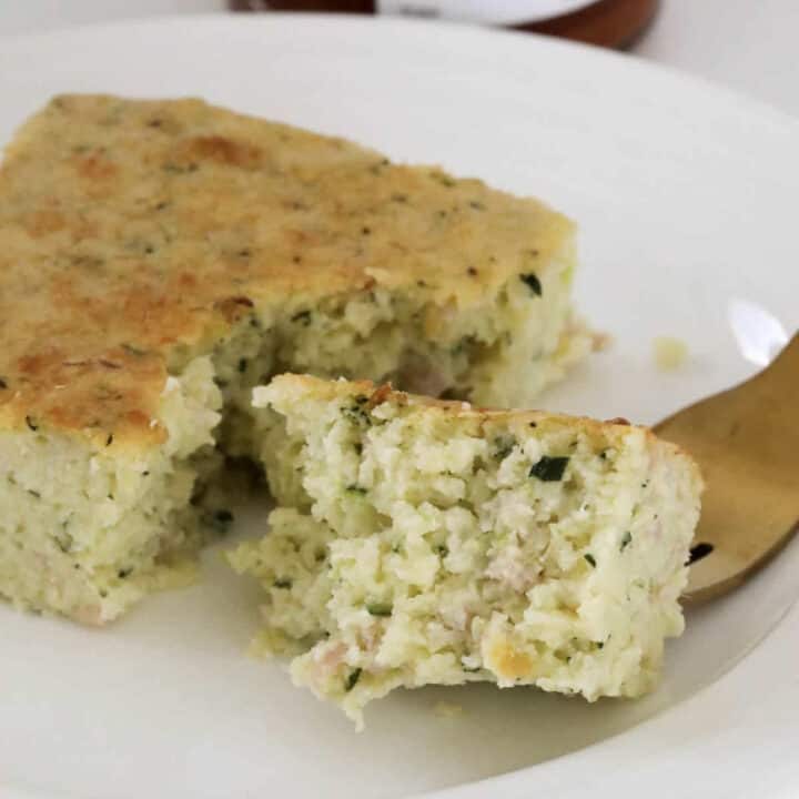 A gold fork with zucchini slice on it.