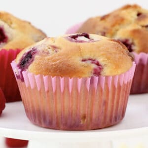 A raspberry muffin in a pink paper case with white chocolate chips.