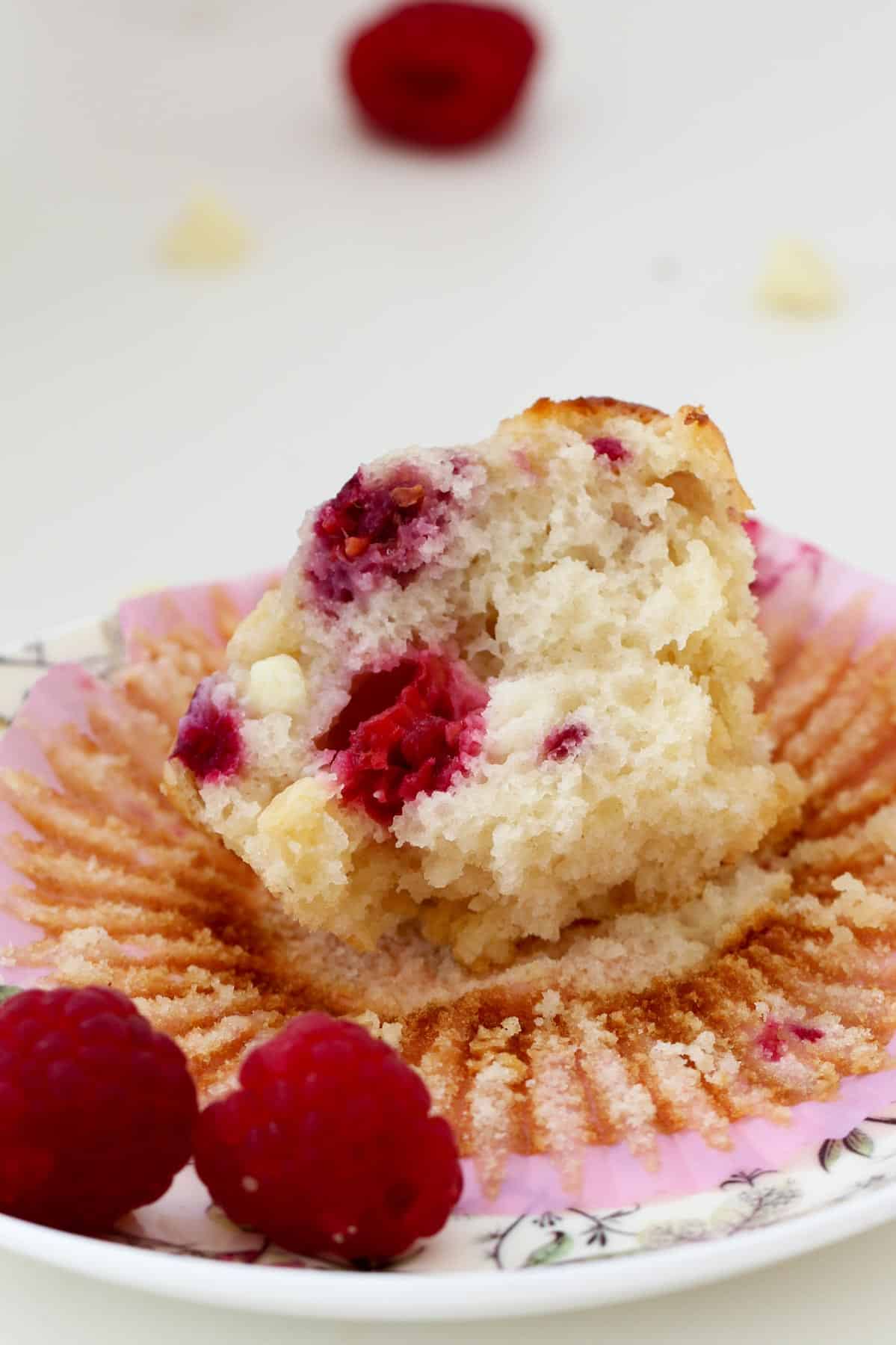 A half eaten muffin with chocolate chips and raspberries throughout.