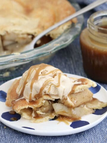 A piece of apple pie with ice cream and caramel sauce.