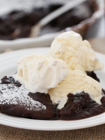 Chocolate self saucing pudding with ice cream on a plate.