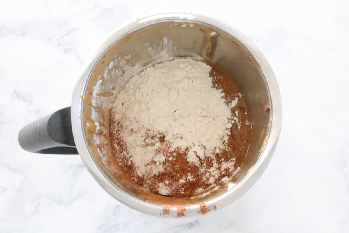 dry ingredients being added to brownie batter in a thermomix bowl.