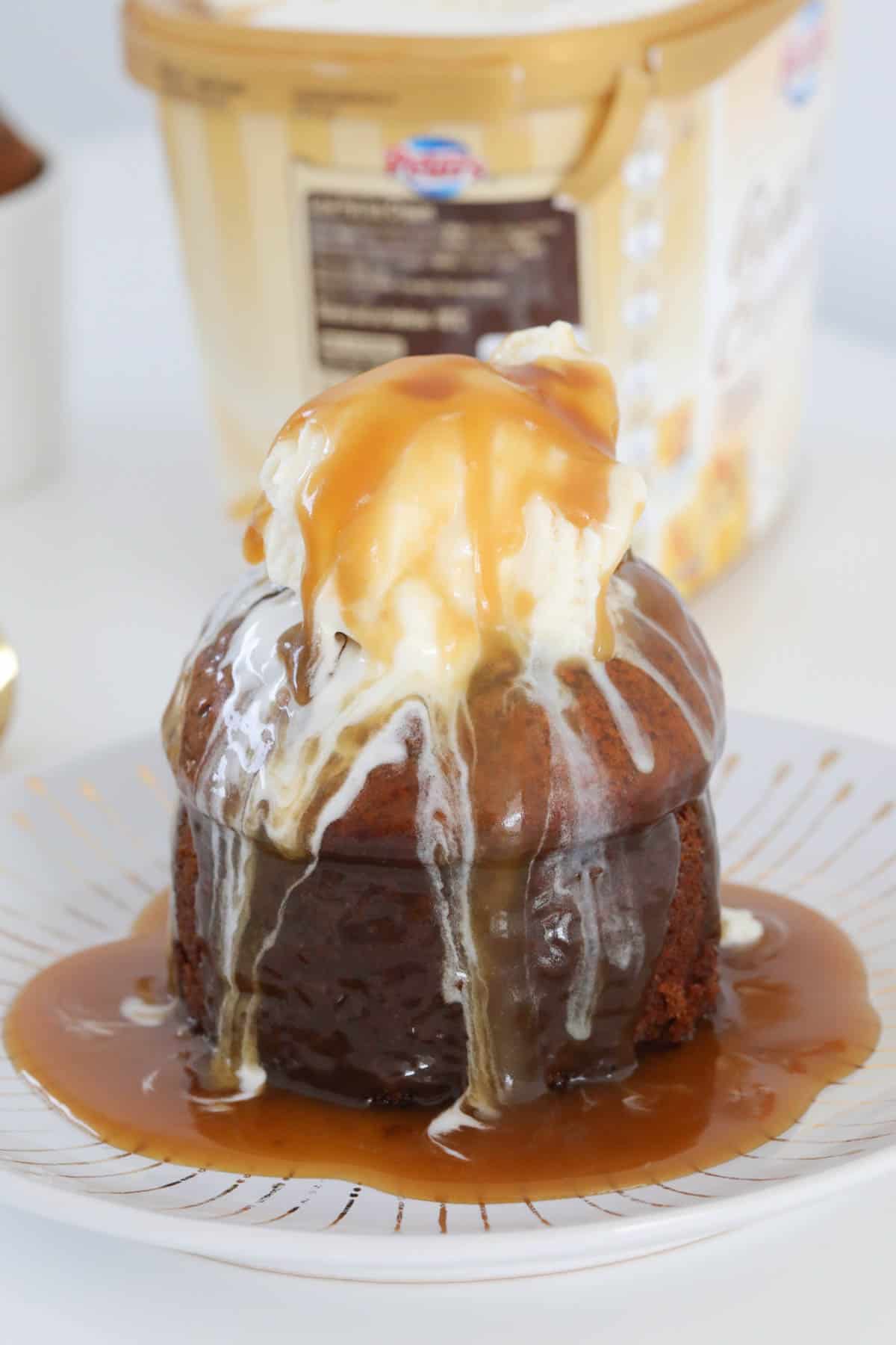 a sticky date pudding on a plate topped with ice cream and caramel sauce.