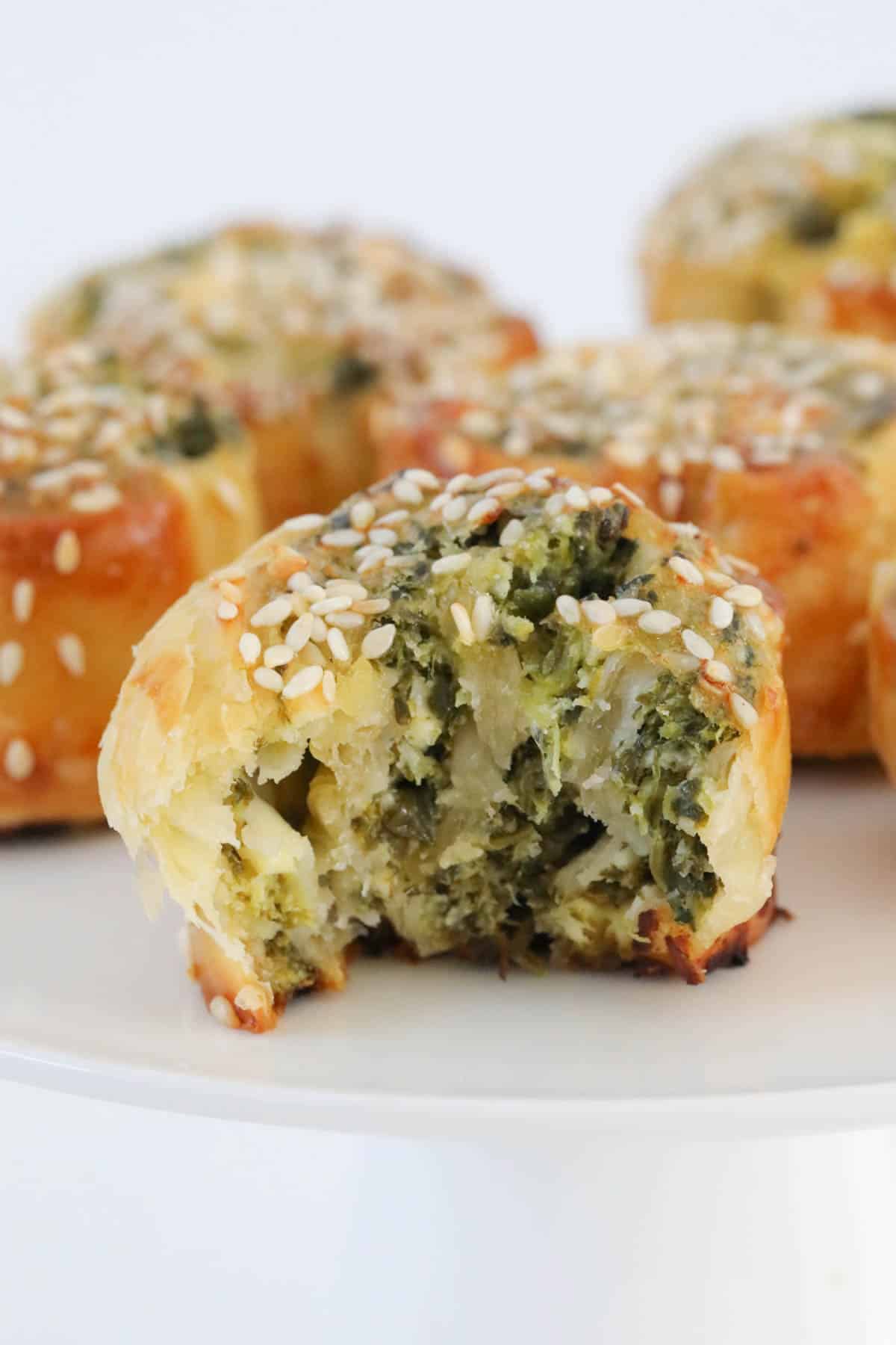 Puff pastry scrolls filled with spinach and feta on a white stand.