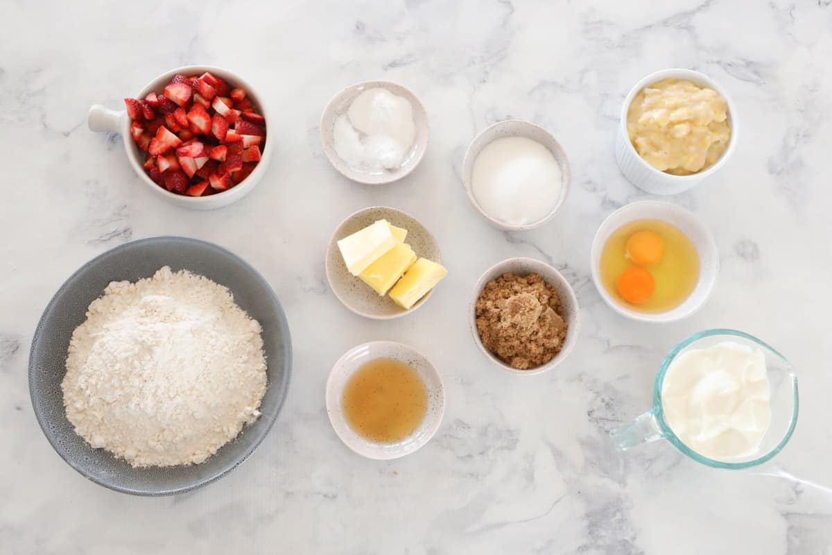 All ingredients for strawberry banana muffins, laid out on a bench top.