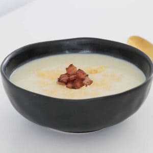 A rustic black bowl filled with Thermomix Cauliflower Soup