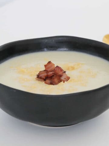 A rustic black bowl filled with Thermomix Cauliflower Soup