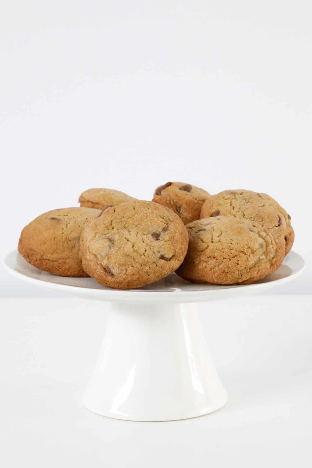 A white cake stand topped with chocolate chip cookies.