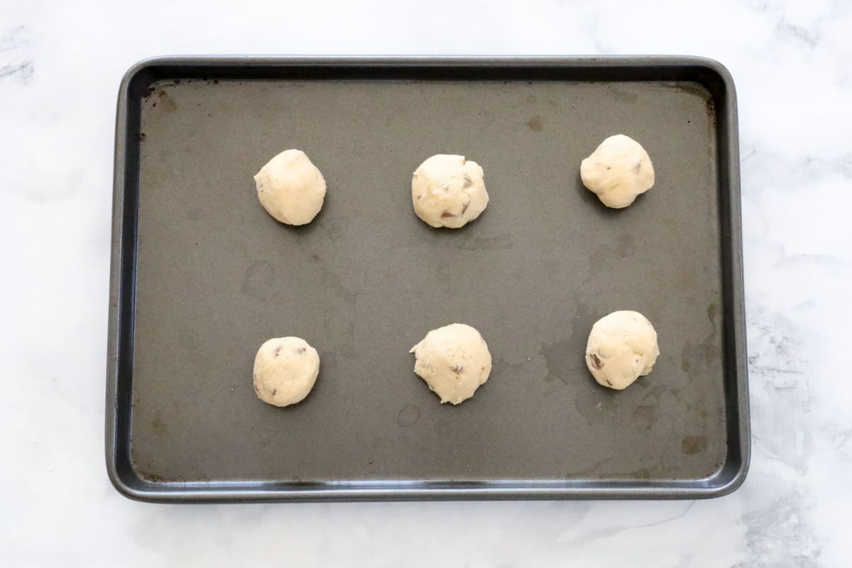 Chocolate chip cookie dough balls on a baking tray.