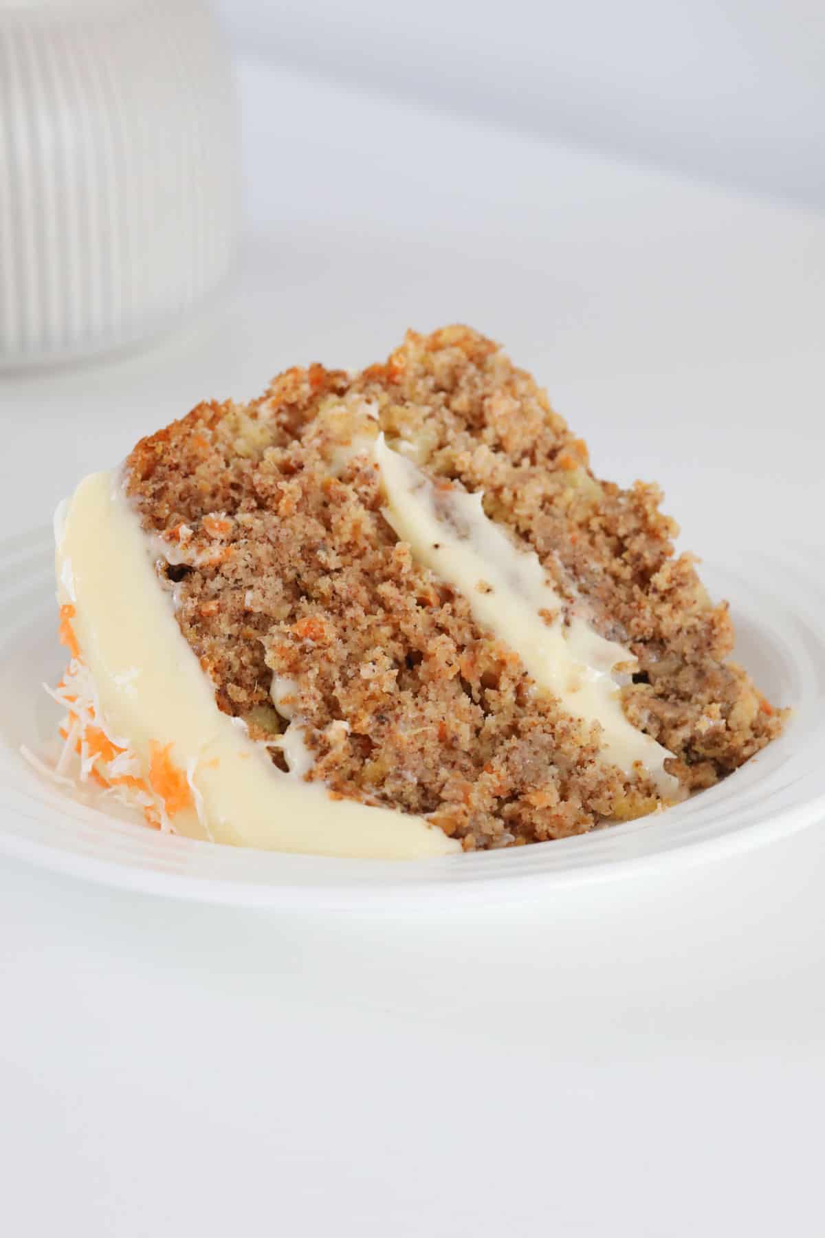 A slice of layered carrot cake with cream cheese frosting.
