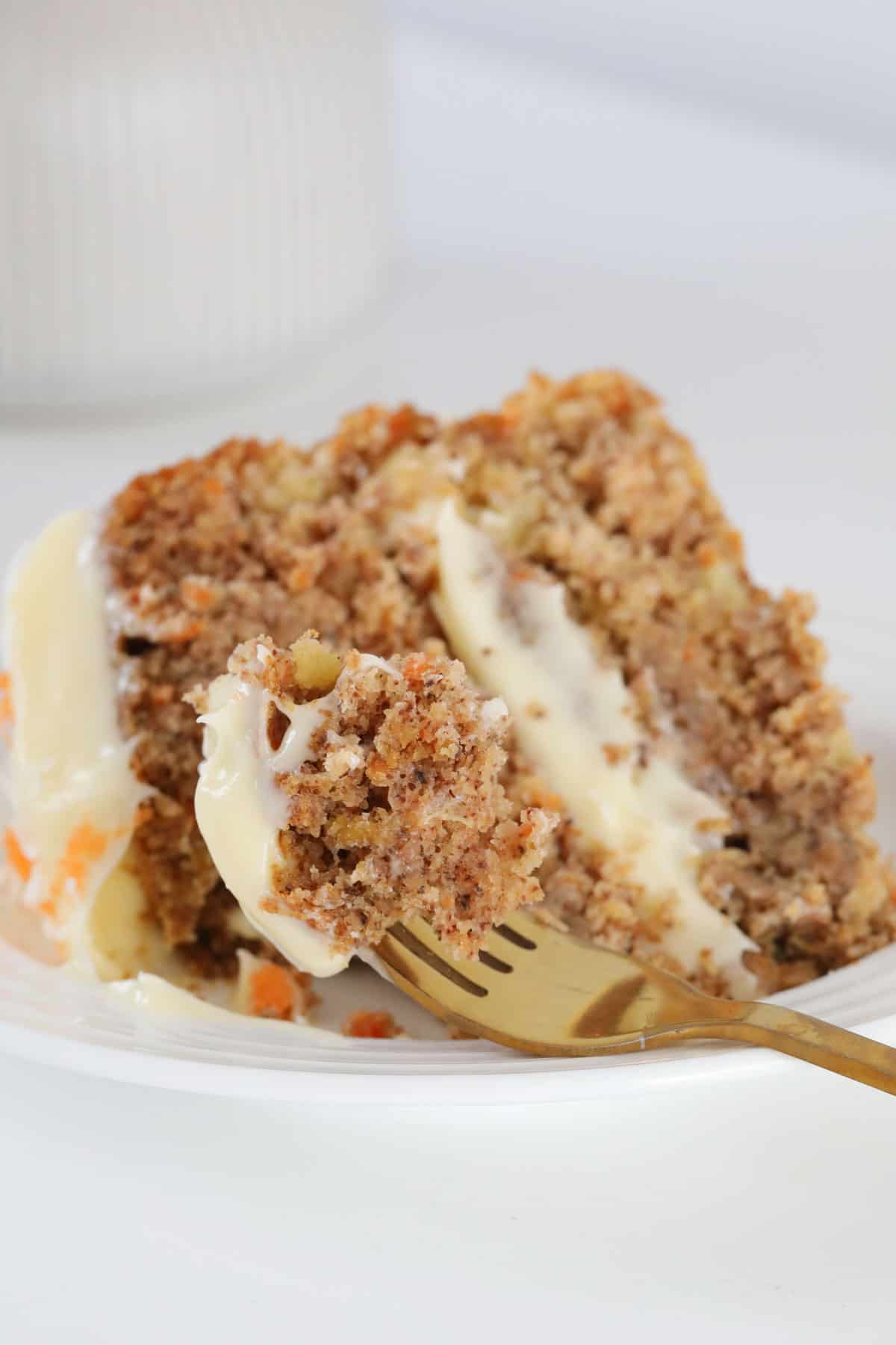 A forkful of carrot cake, resting on a plate.
