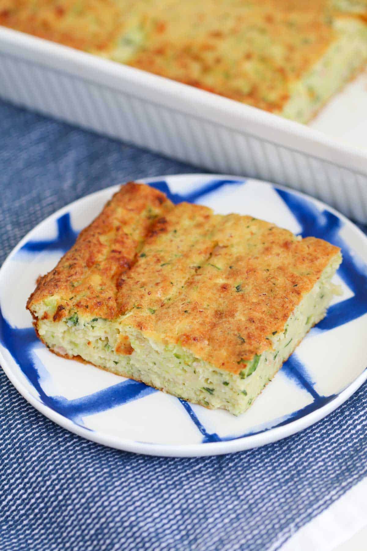 A piece of zucchini egg quiche slice on a blue and white plate.