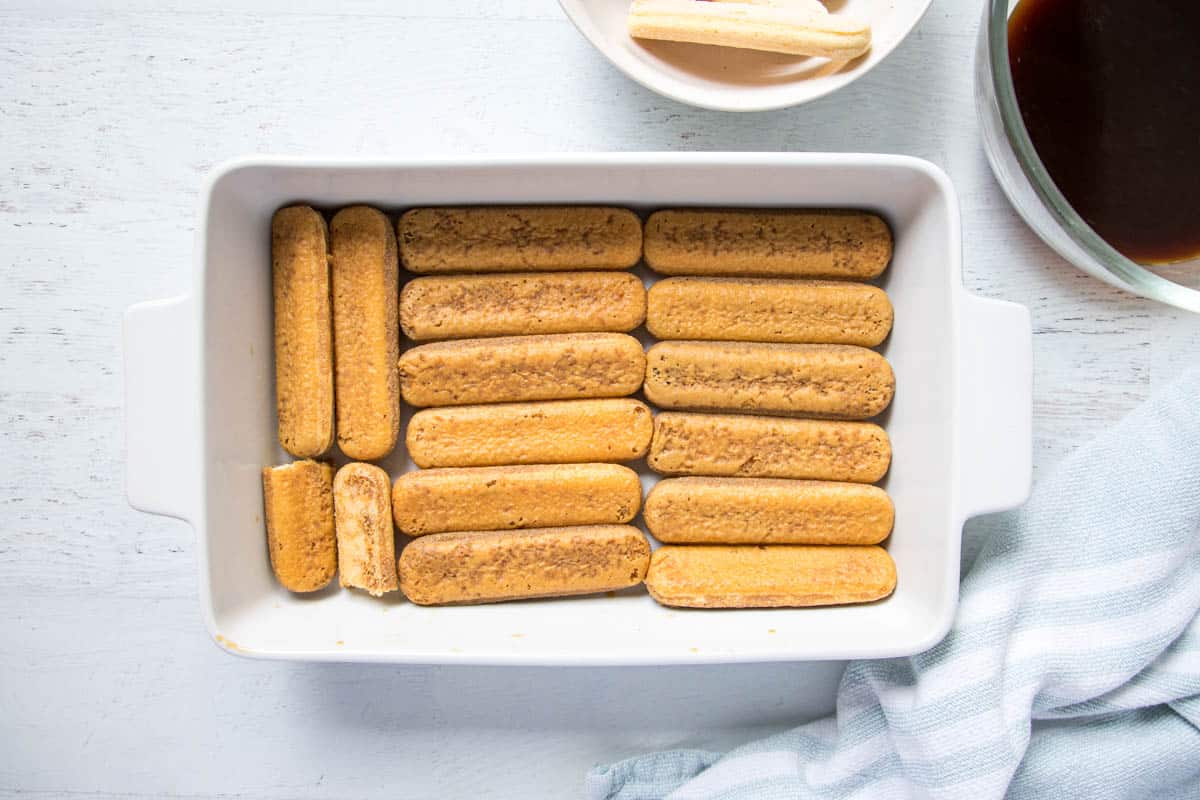 ladyfinger sponges soaked in coffee arranged in a white dish