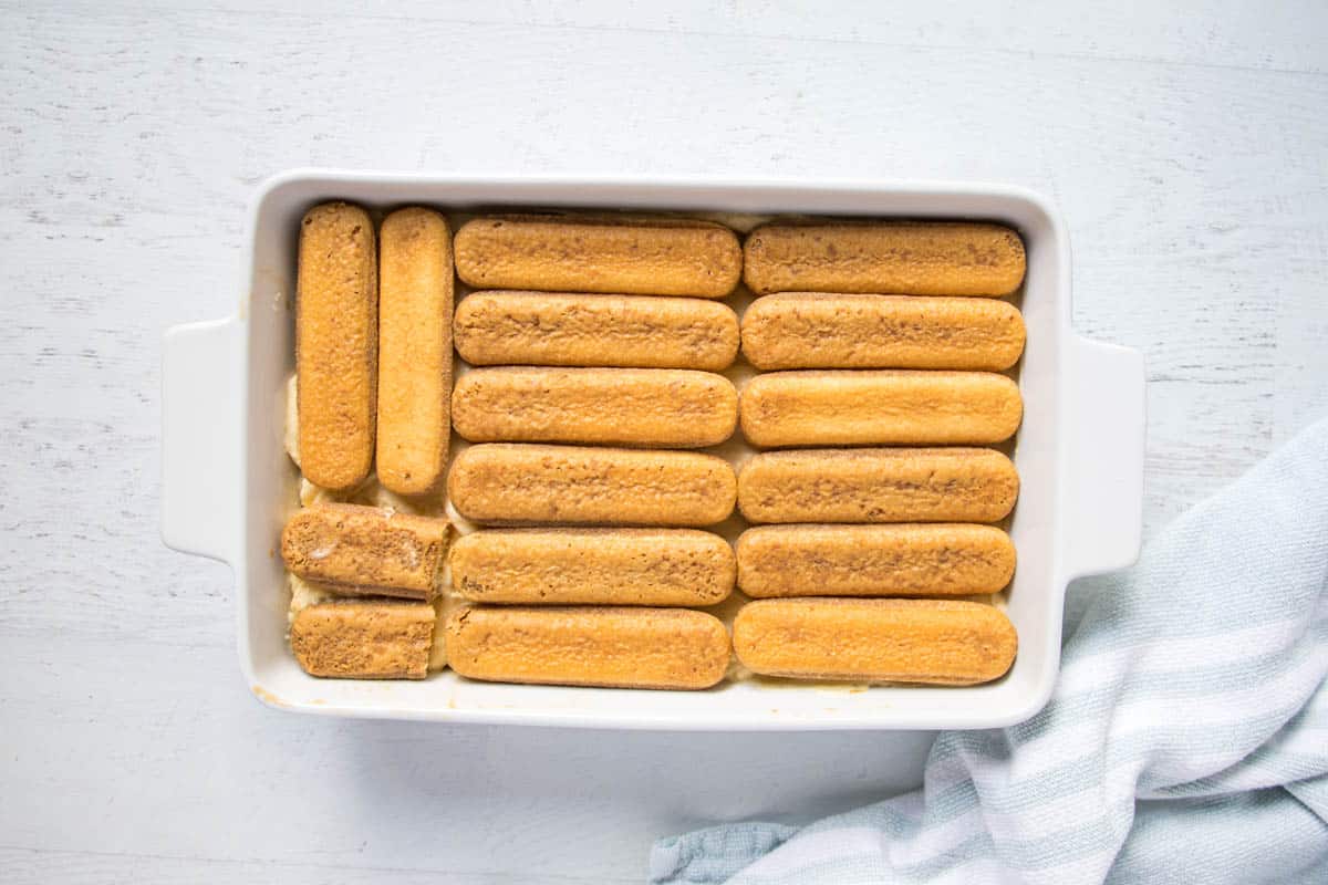 ladyfinger sponges soaked in coffee and arranged in a white dish.