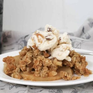 A plate topped with crunchy oat crumble, stewed apples and ice-cream.