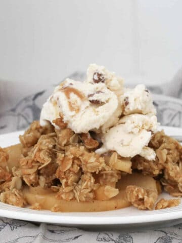 A plate topped with crunchy oat crumble, stewed apples and ice-cream.
