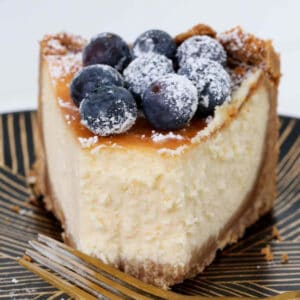 A half eaten piece of New York cheesecake with blueberries on top.