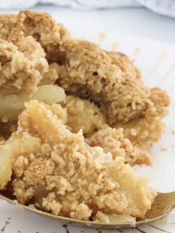 A forkful of lightly stewed apples with crunchy oat crumble on top.