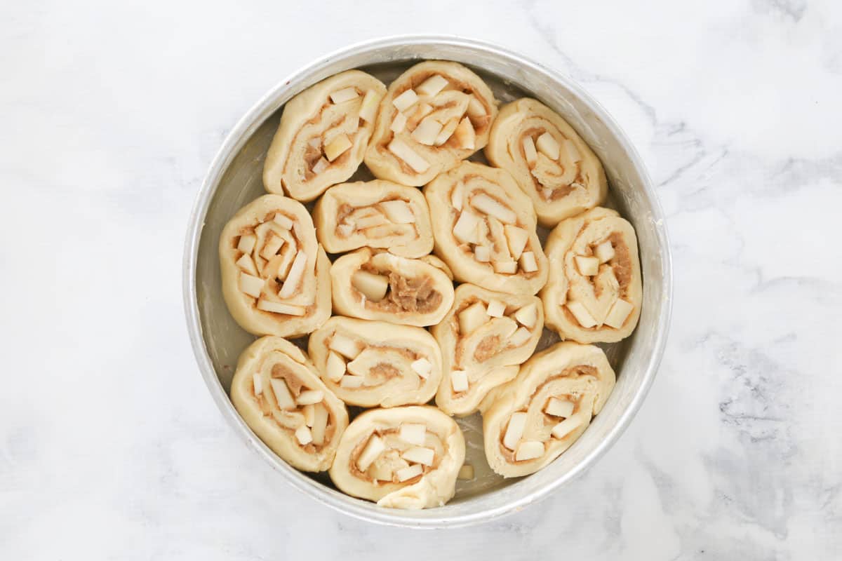 Cut scrolls placed together in a round tin, ready to bake.