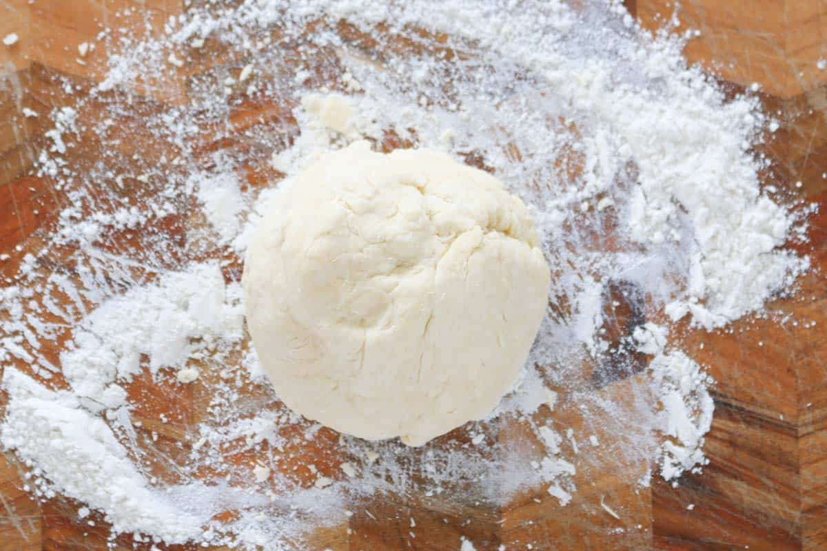 A ball of dough on a floured wooden board.