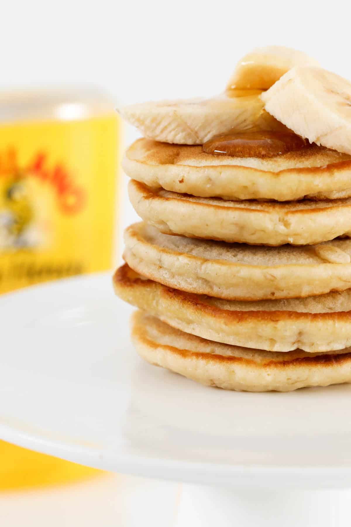 A side view of a stack of fluffy mini pancakes with sliced banana on top.