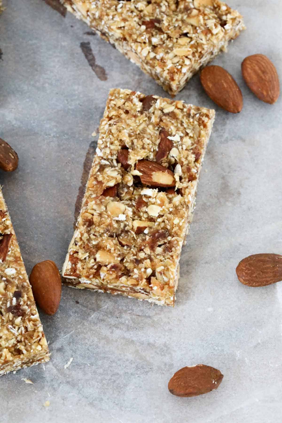 Pieces of date protein bars and roasted almonds on baking paper.