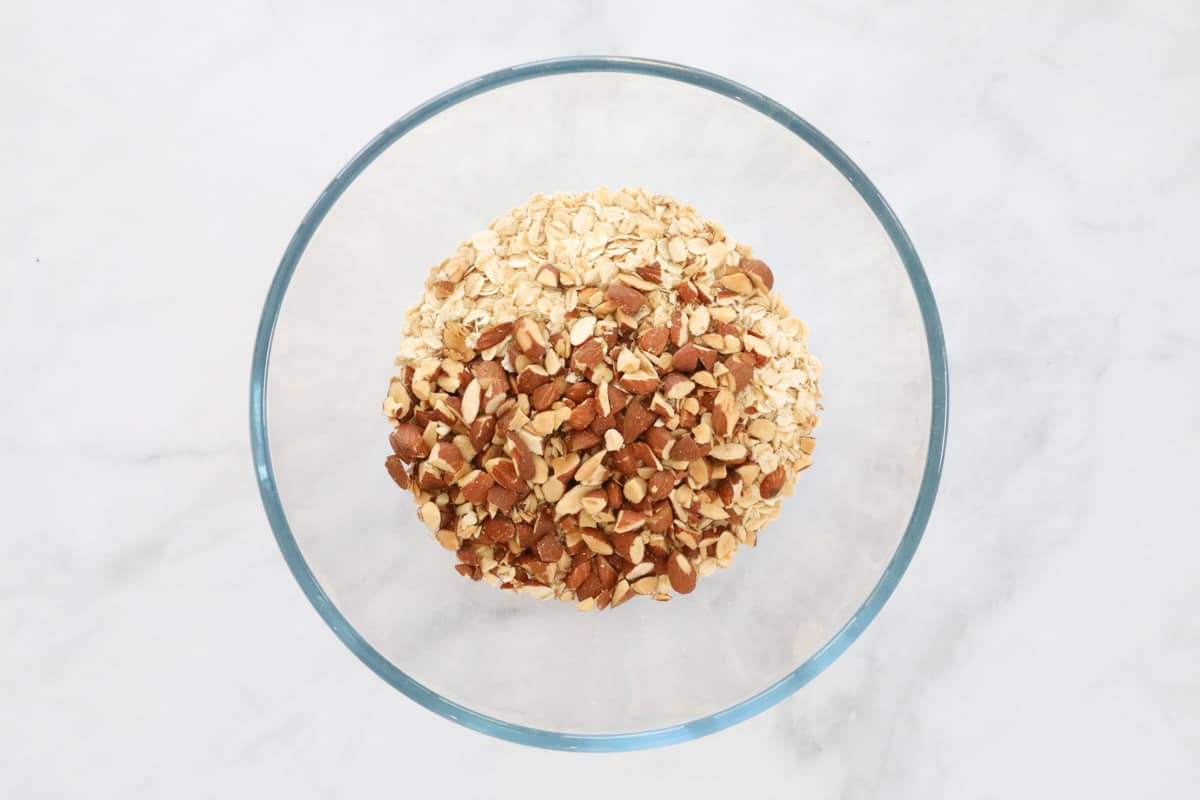Chopped almonds and rolled oats in a mixing bowl.