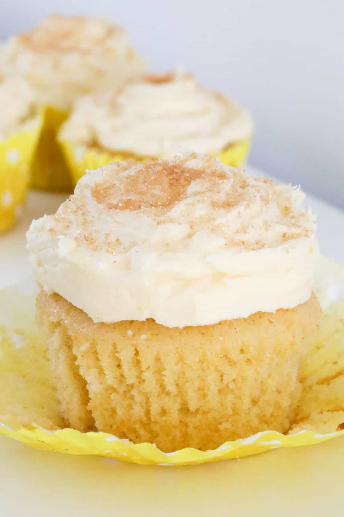 A close up shot of a fluffy lemon cupcake with the paper case opened up.