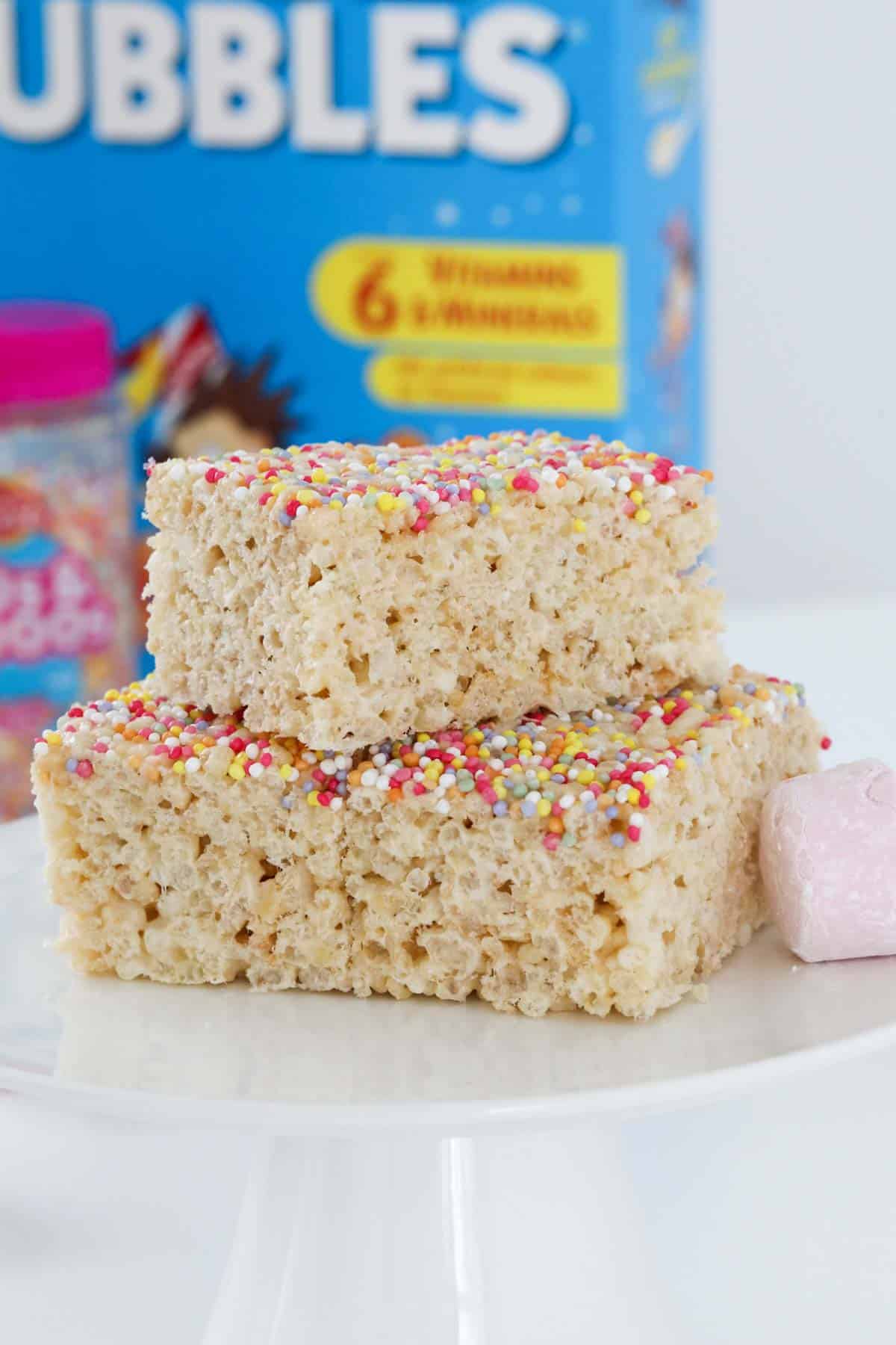 A stack of 3 pieces of marshmallow slice with puffed rice and sprinkled with 100's & 1000's.