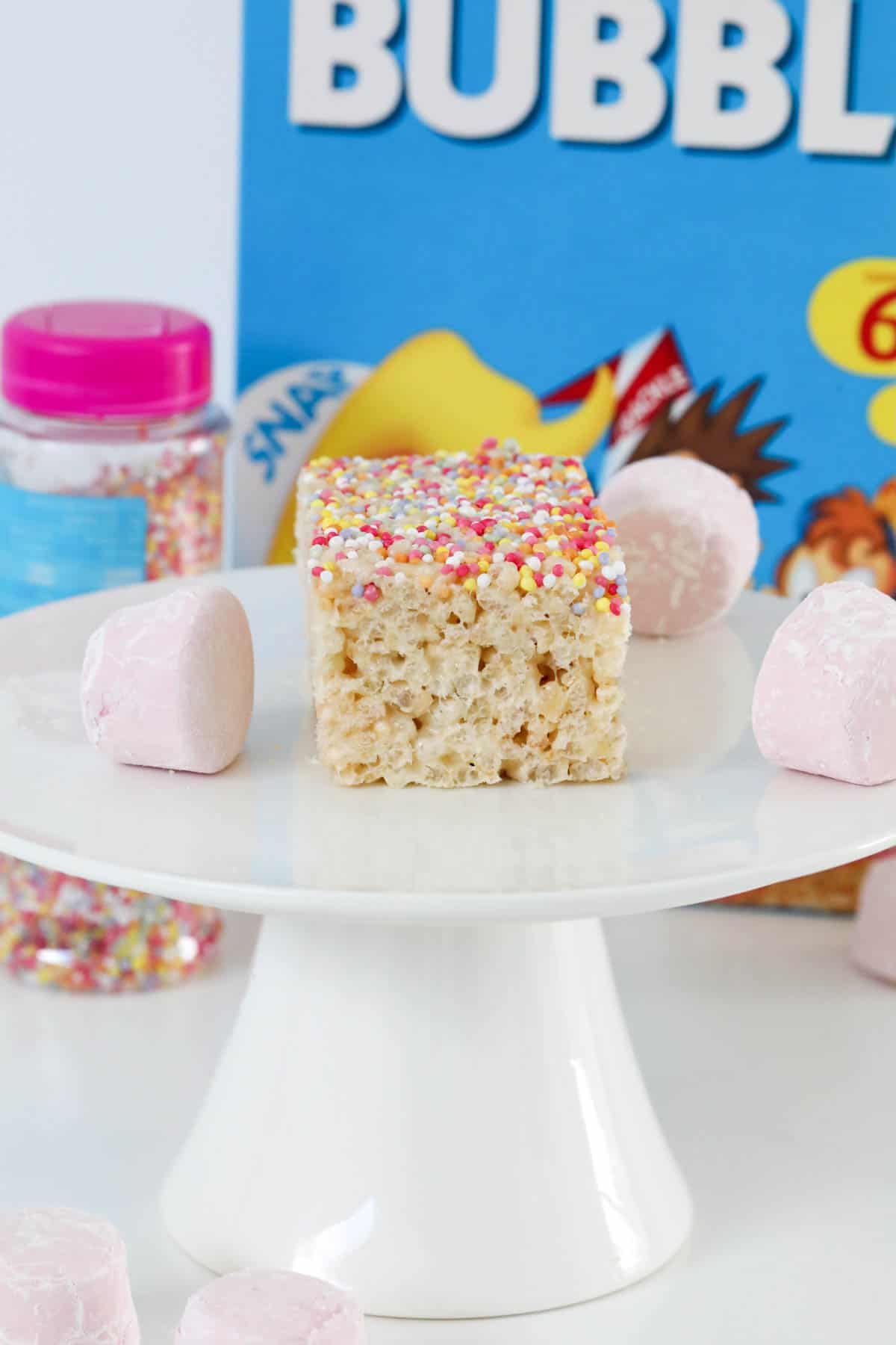 Homemade rice krispie treats in front of a packet of puffed rice with marshmallows on the side.