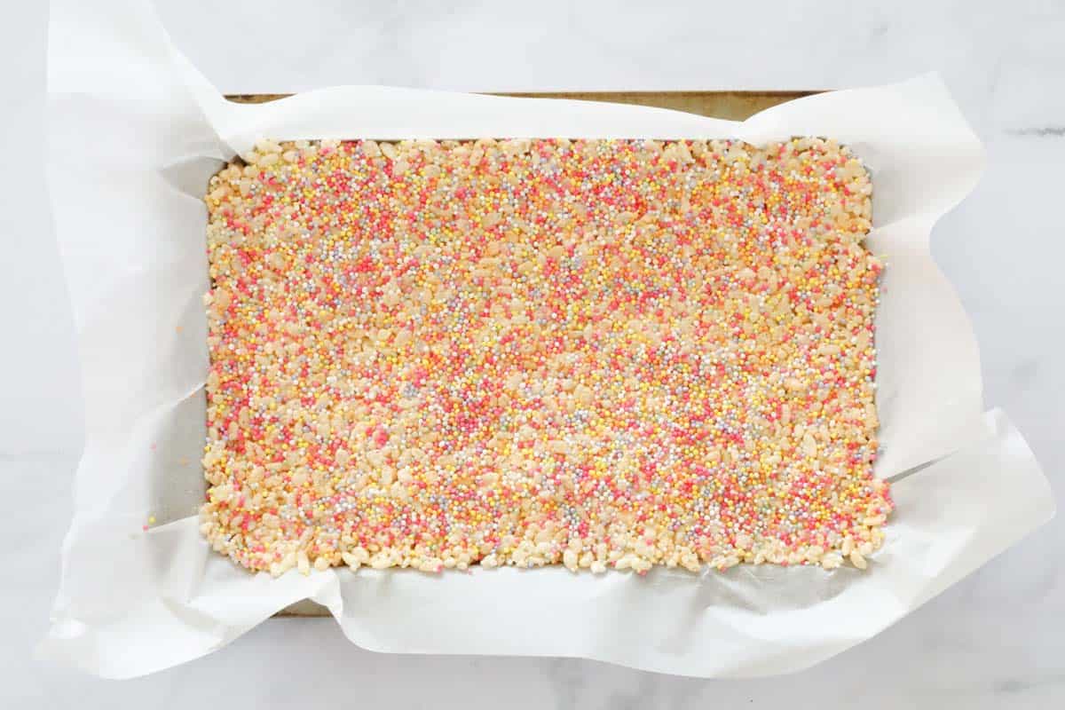 A rice krispie slice with 100s and 1000s on top, pressed into a slice tin.