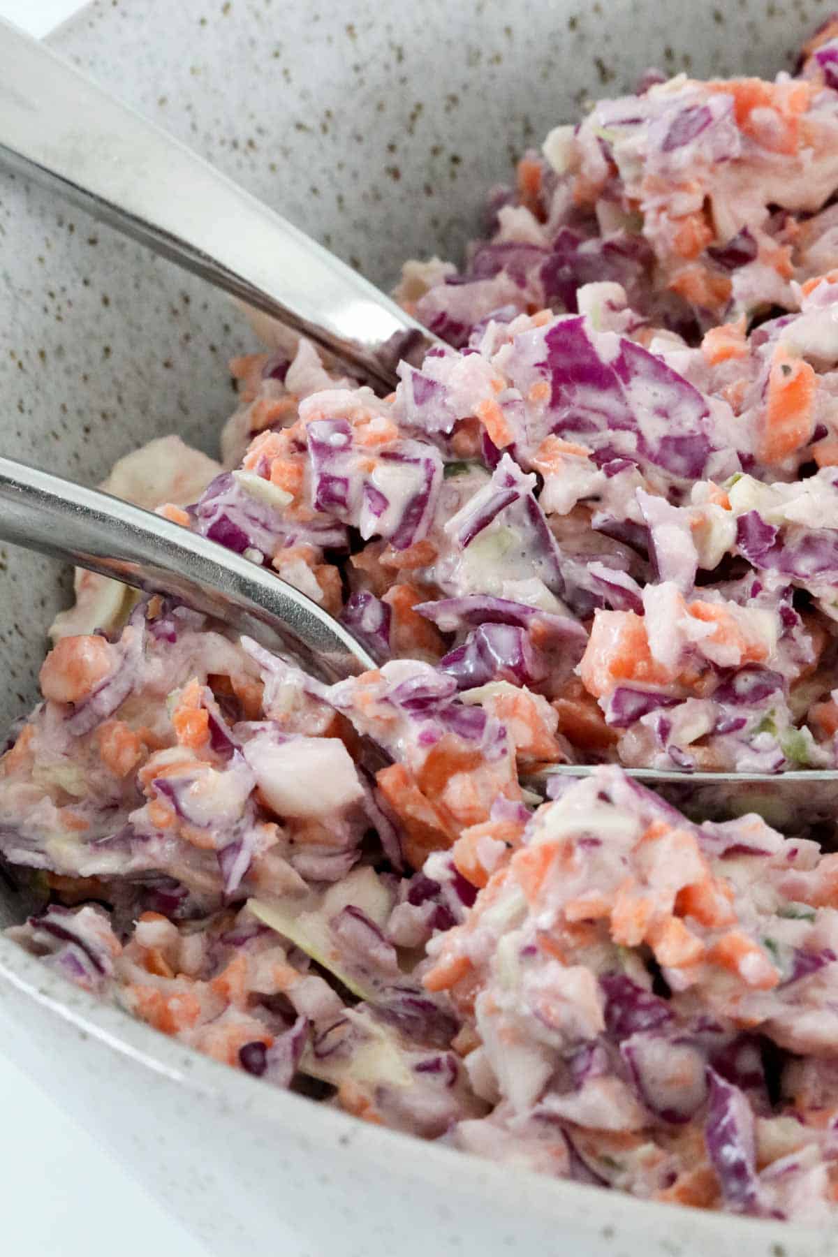 A bowl of purple and green cabbage with carrots and a creamy dressing.