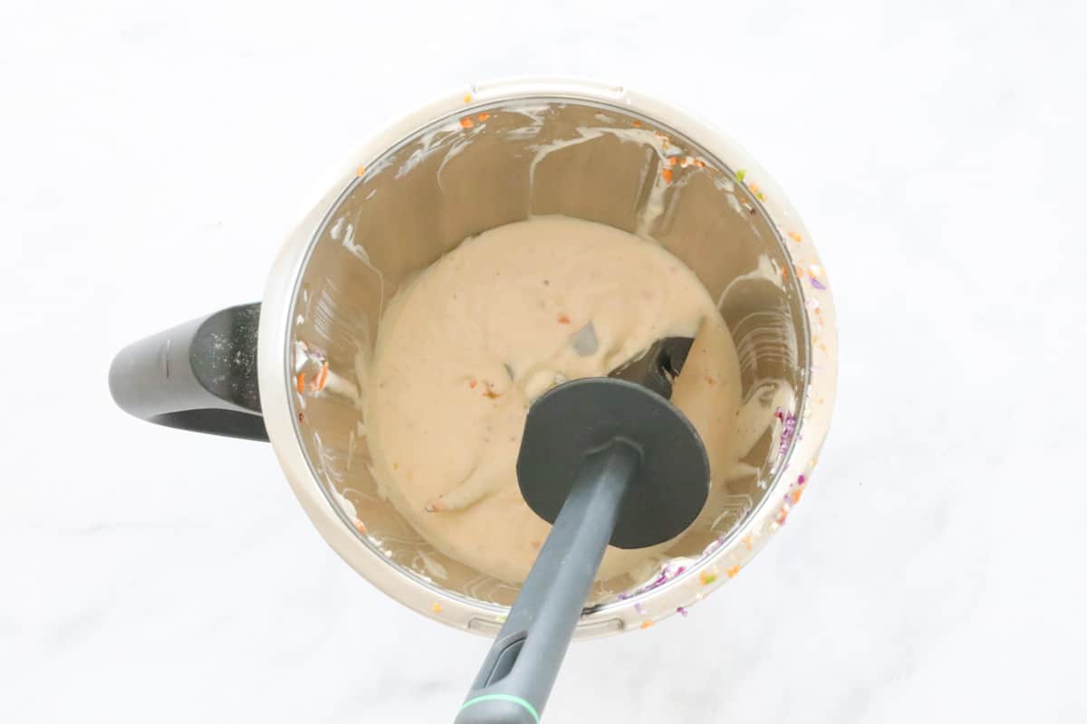 Creamy coleslaw dressing in a Thermomix with a spatula.