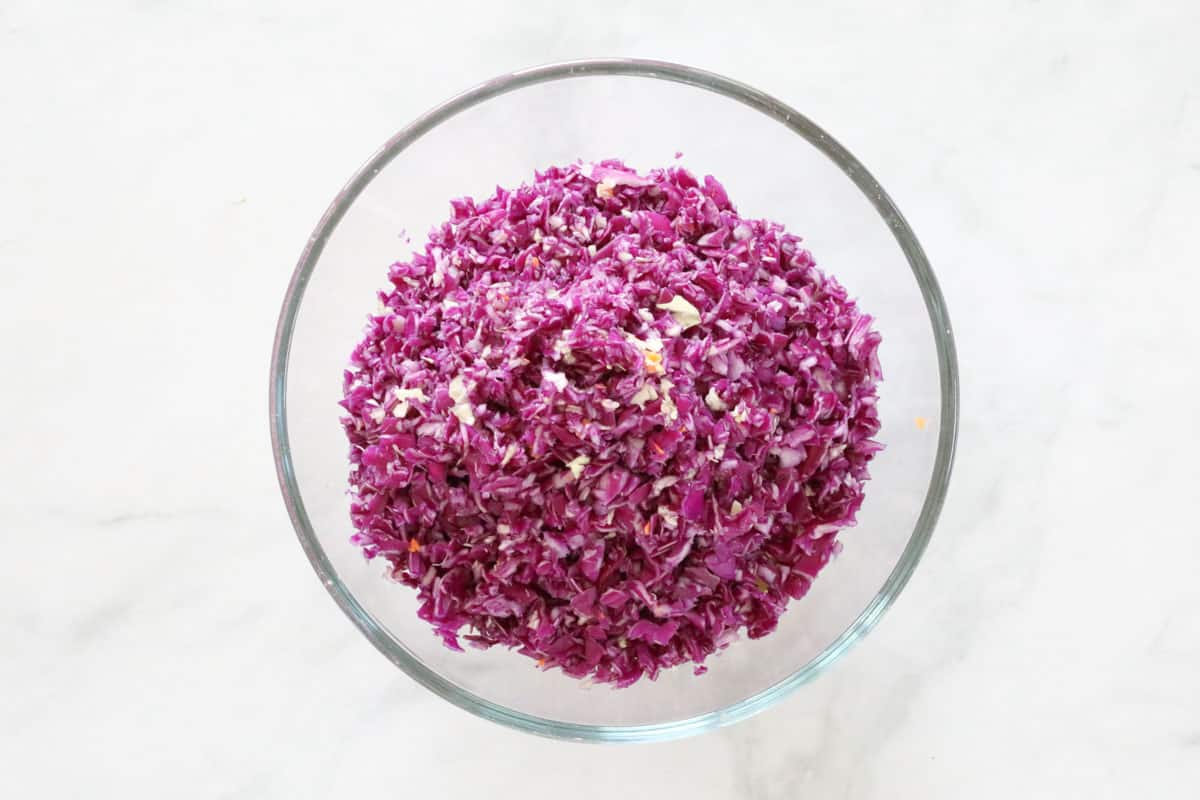 Chopped purple cabbage added to a glass bowl.