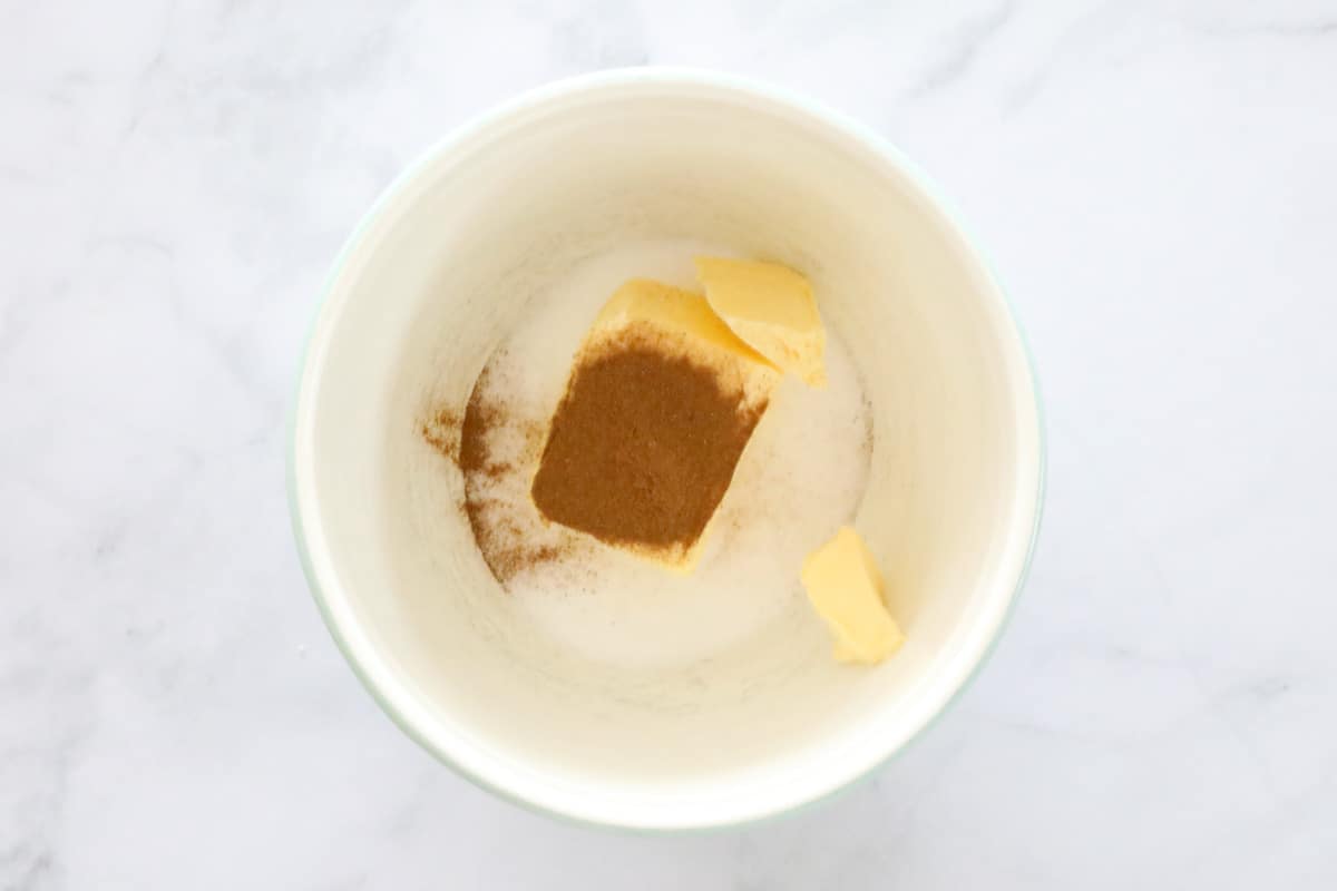 Butter, sugar and cinnamon placed in a white bowl.
